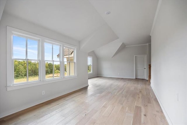 additional living space with light wood-type flooring, baseboards, and lofted ceiling