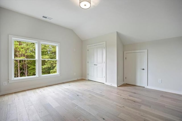 additional living space featuring light wood-style floors, lofted ceiling, visible vents, and baseboards