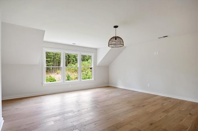 additional living space featuring lofted ceiling, baseboards, visible vents, and wood finished floors