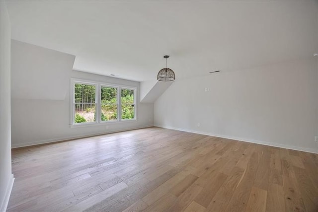 bonus room with vaulted ceiling, light wood finished floors, and baseboards