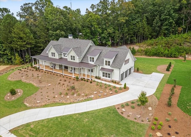 view of front facade with metal roof, a porch, driveway, a front lawn, and a standing seam roof