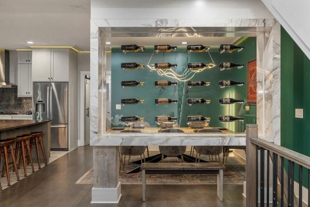 bar with wood-type flooring, wall chimney range hood, white cabinets, stainless steel refrigerator with ice dispenser, and backsplash