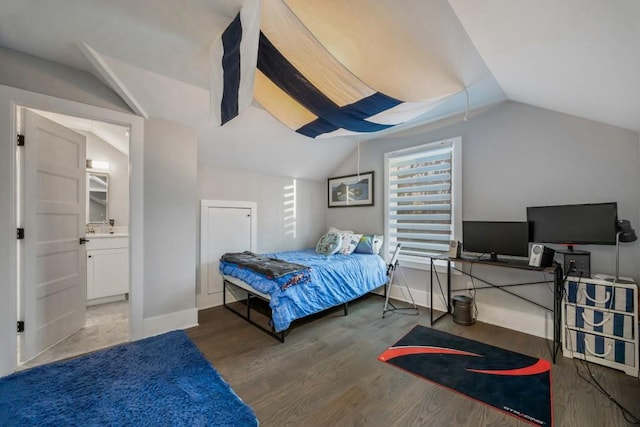 bedroom featuring hardwood / wood-style floors, lofted ceiling, and ensuite bath