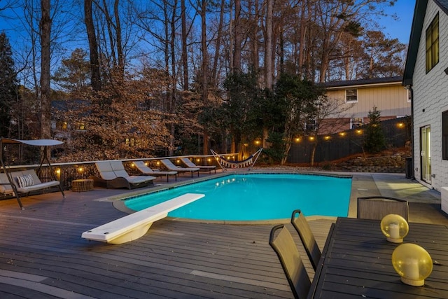 view of pool with a deck and a diving board