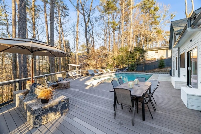 deck featuring a fenced in pool and an outdoor fire pit