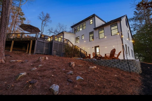 back house at dusk with central AC unit and a deck