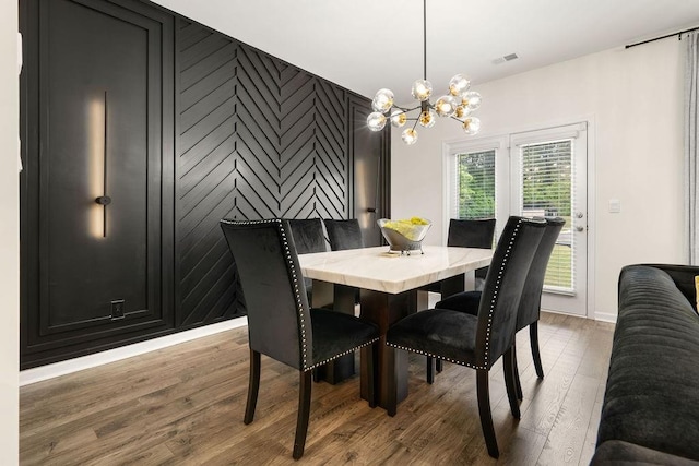 dining space with hardwood / wood-style flooring and a notable chandelier