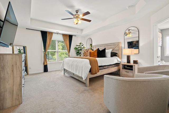 carpeted bedroom with ceiling fan and a tray ceiling