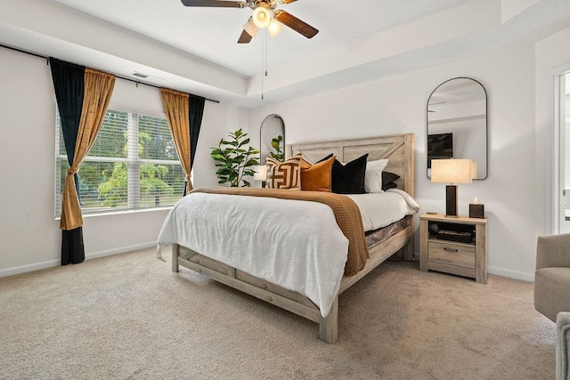 bedroom with a tray ceiling, ceiling fan, and light colored carpet