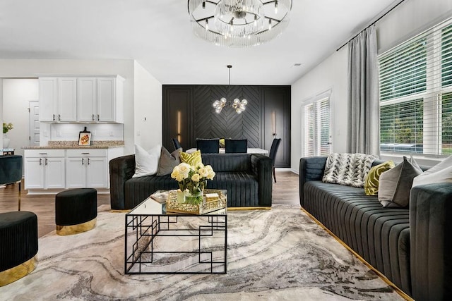 living room with light wood-type flooring and an inviting chandelier