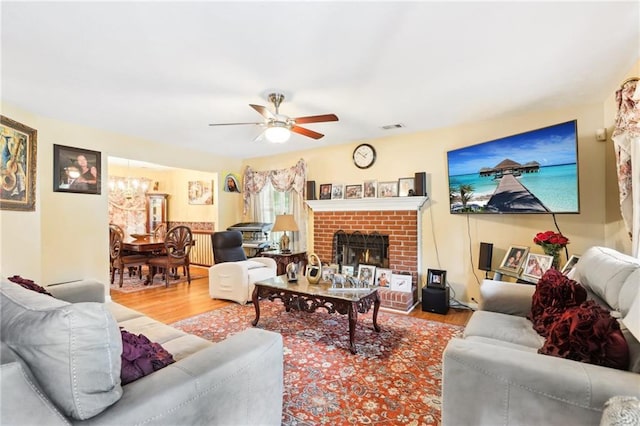 179 Parkside Dr, Stockbridge, GA 30281 - living room with wood finished floors, ceiling fan, a chandelier, and a brick fireplace