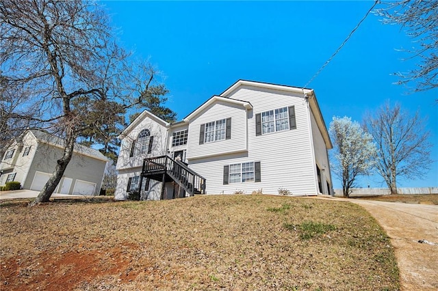 exterior space with stairway, a detached garage, and a front lawn