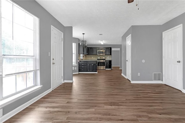 unfurnished living room with ceiling fan with notable chandelier, dark hardwood / wood-style floors, and a textured ceiling