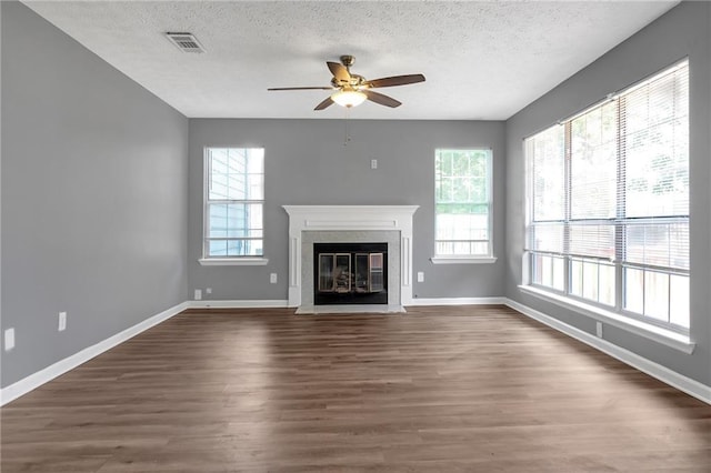 unfurnished living room with ceiling fan, a textured ceiling, and dark hardwood / wood-style flooring