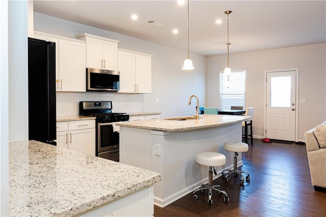 kitchen featuring stainless steel appliances, white cabinetry, sink, and pendant lighting