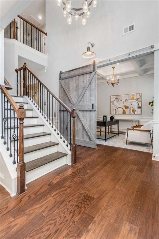 2544 Thompson Rd NE, Brookhaven, GA 30319 - staircase with a chandelier, wood finished floors, a towering ceiling, a barn door, and beam ceiling