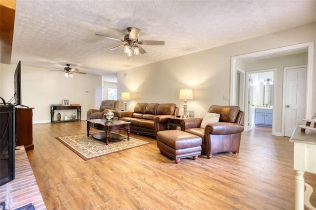 living room with a textured ceiling, hardwood / wood-style flooring, and ceiling fan