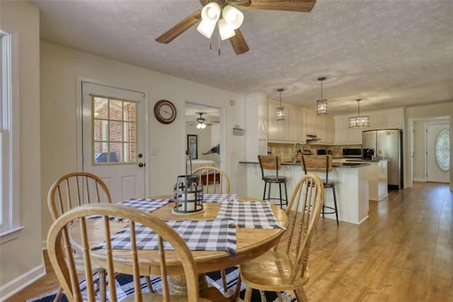 dining area featuring light hardwood / wood-style floors, ceiling fan, and a textured ceiling