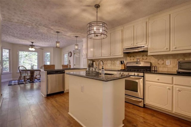 kitchen with stainless steel appliances, dark hardwood / wood-style flooring, pendant lighting, and a kitchen island