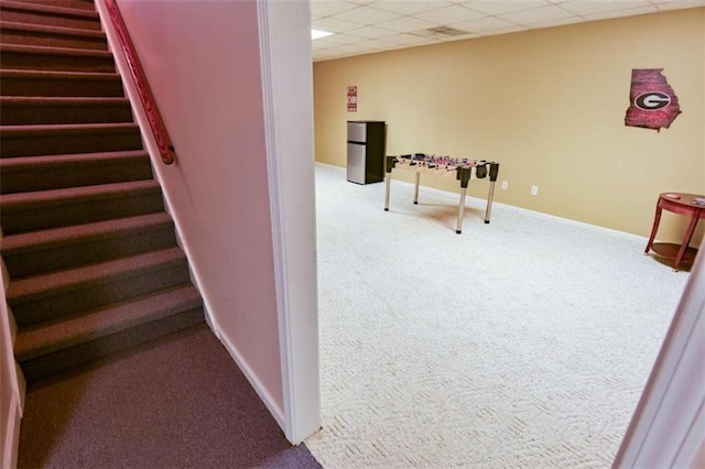 stairs featuring a paneled ceiling and carpet