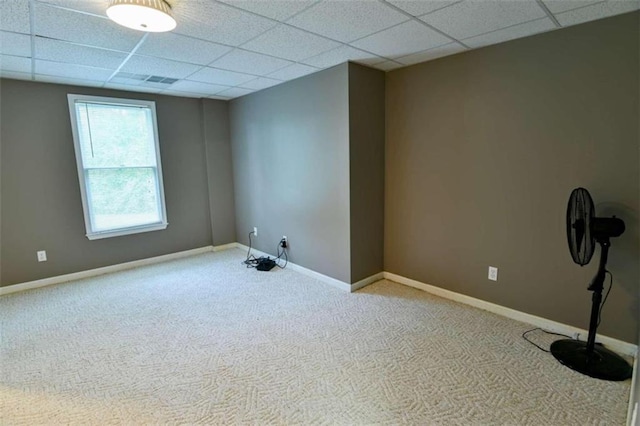 spare room with a paneled ceiling and light carpet