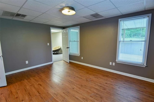 unfurnished room with a drop ceiling and wood-type flooring