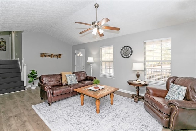 living room featuring a textured ceiling, ceiling fan, vaulted ceiling, and light hardwood / wood-style flooring