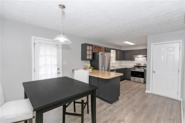 kitchen featuring a textured ceiling, pendant lighting, light wood-type flooring, gray cabinetry, and appliances with stainless steel finishes