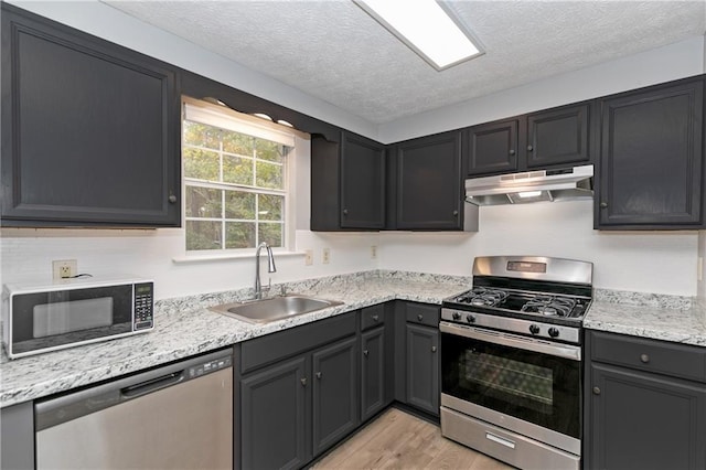 kitchen featuring stainless steel appliances, a textured ceiling, sink, and light wood-type flooring