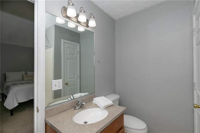 bathroom with a textured ceiling, vanity, and toilet