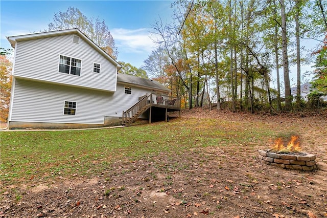 rear view of property with a fire pit, a wooden deck, and a yard