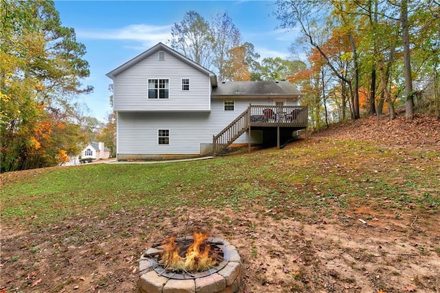 back of property featuring a lawn, a fire pit, and a wooden deck