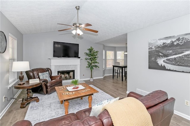 living room featuring a premium fireplace, a textured ceiling, and light hardwood / wood-style flooring