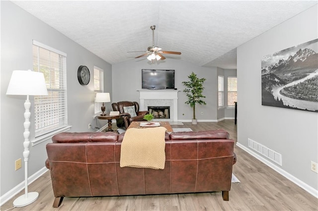 living room with light hardwood / wood-style floors, ceiling fan, a healthy amount of sunlight, and lofted ceiling