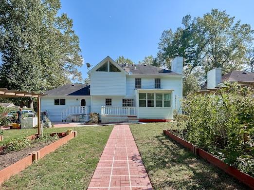 back of property featuring a pergola and a lawn