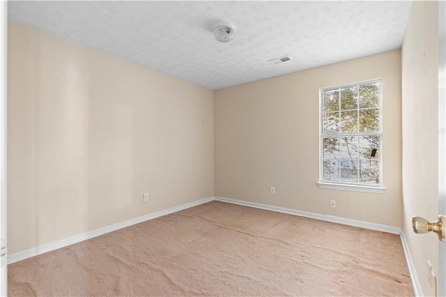 spare room with a textured ceiling and light carpet