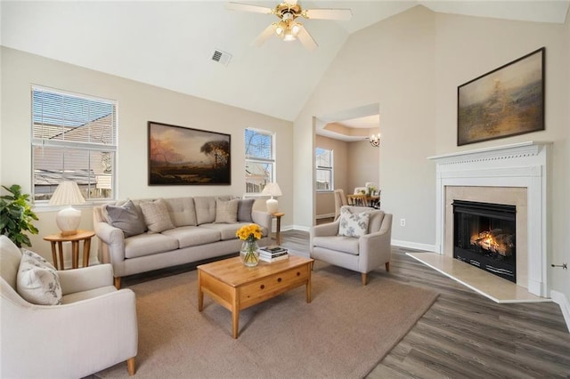 living area with a ceiling fan, wood finished floors, visible vents, high vaulted ceiling, and baseboards