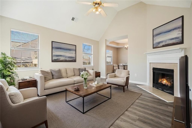 living room with wood finished floors, a ceiling fan, visible vents, high vaulted ceiling, and baseboards