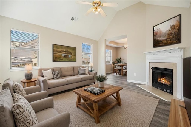 living room featuring a ceiling fan, baseboards, visible vents, high vaulted ceiling, and dark wood finished floors