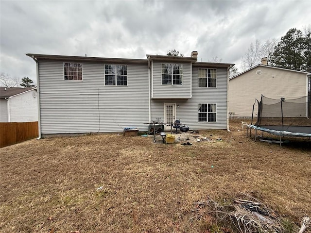 back of property featuring a trampoline and a yard