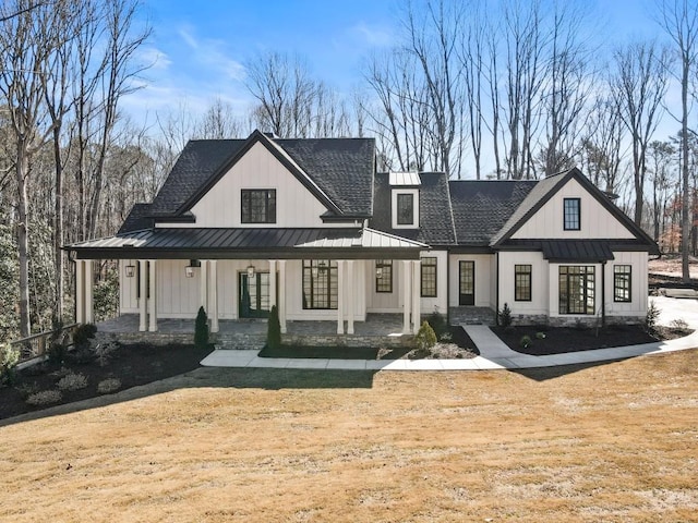 back of property with covered porch, roof with shingles, metal roof, and a standing seam roof