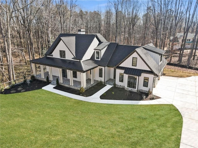 modern farmhouse with metal roof, a front lawn, a standing seam roof, and a chimney