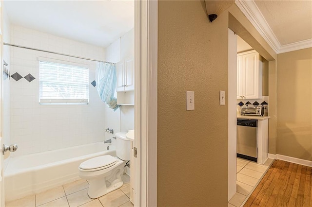 bathroom with tile patterned flooring, toilet, crown molding, and tiled shower / bath