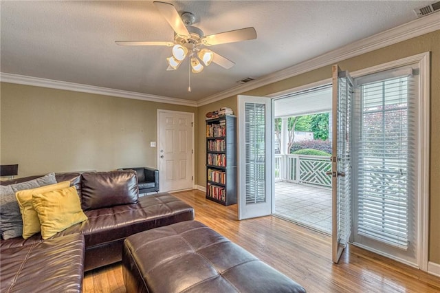 living room featuring light hardwood / wood-style floors, ceiling fan, and crown molding