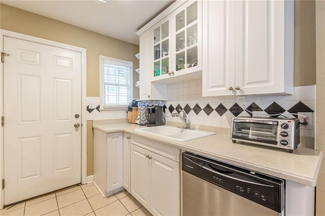 kitchen featuring white cabinetry, sink, light tile patterned floors, and stainless steel dishwasher