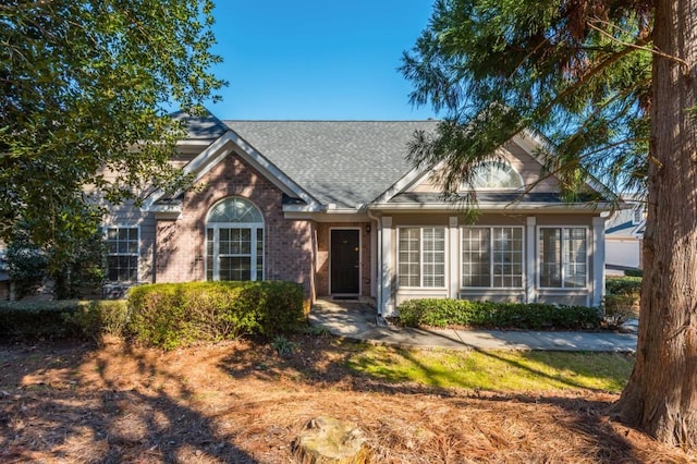 view of front of property with brick siding and roof with shingles