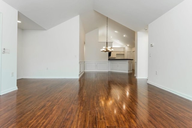 unfurnished living room featuring dark wood finished floors, a notable chandelier, baseboards, and high vaulted ceiling