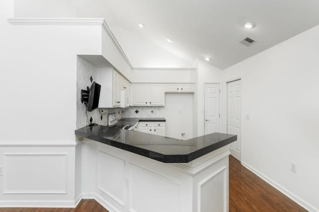 kitchen with visible vents, range with electric stovetop, dark countertops, and a peninsula