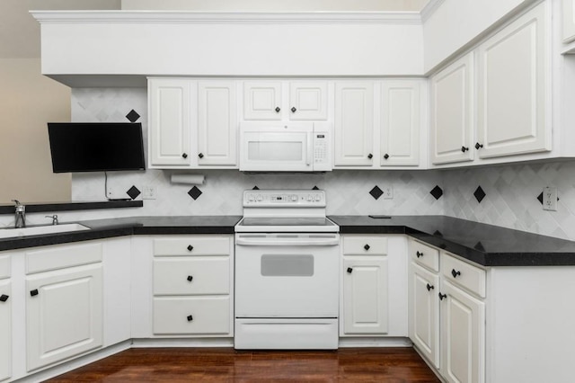 kitchen featuring white appliances, white cabinets, dark countertops, and a sink