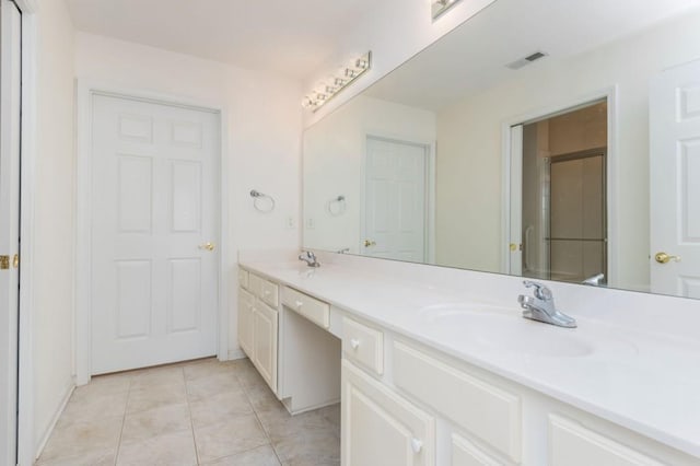 bathroom with visible vents, double vanity, a sink, tile patterned floors, and a shower with door